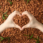 Hands making heart symbol over scattered almonds